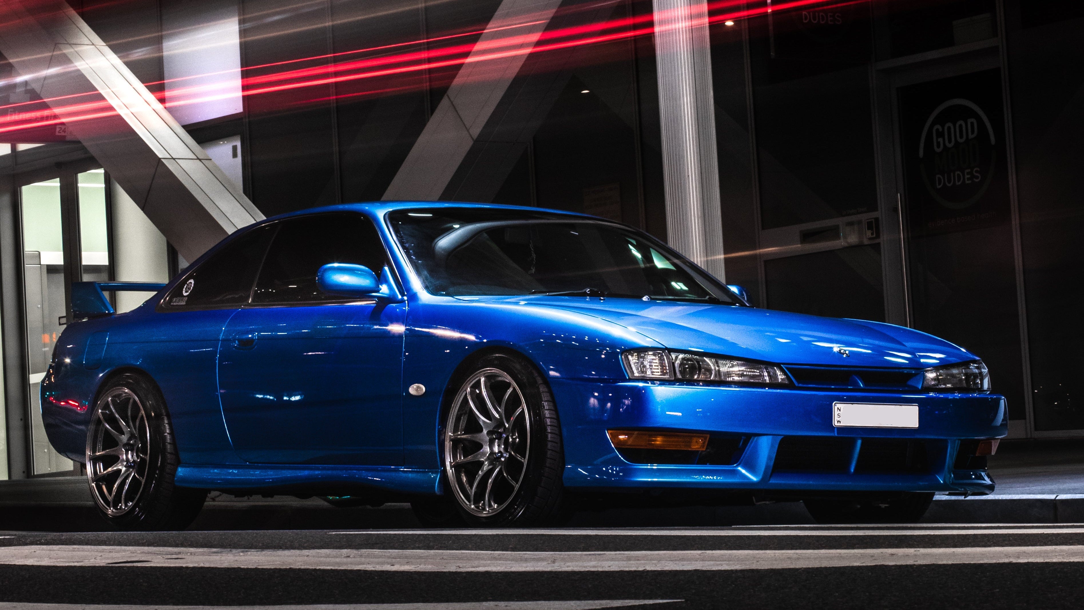 Blue sports car parked in front of a modern building with light streaks